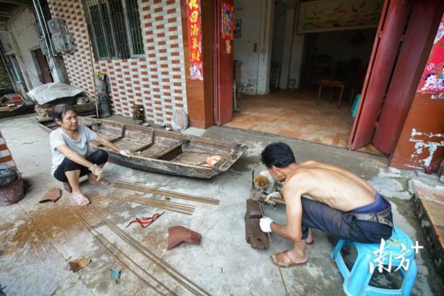 在飞来峡镇江口社区下渡街，村民正在修补小艇。村民告诉记者，近日居委会为村民免费供饭。梁素雅 摄